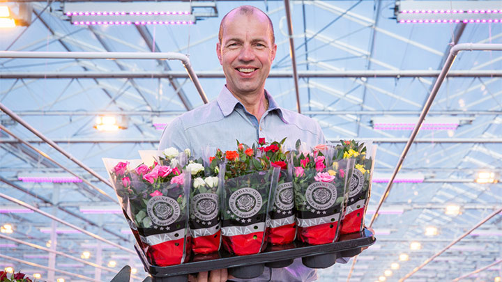 Leo van der Harg poseert met kleurige bloemen in zijn handen.