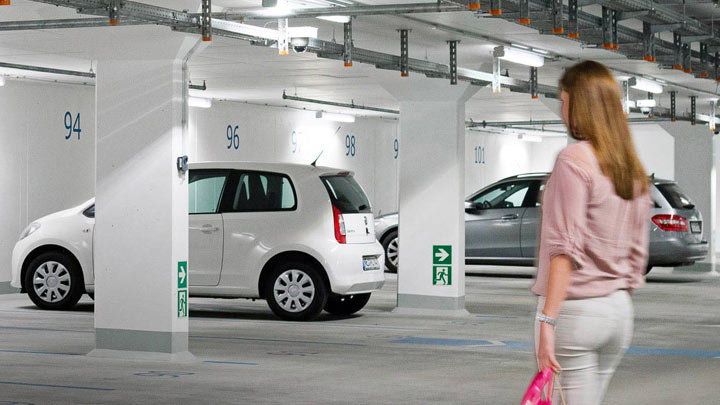 Een vrouw loopt naar haar auto in een goed verlichte parkeergarage 