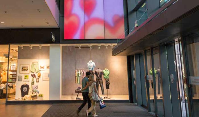Twee mensen bewonderen het voortdurende veranderende Luminous textile-paneel in winkelcentrum Centrum Galerie