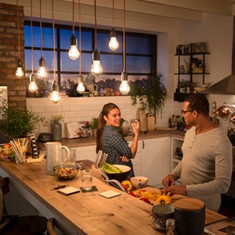 Een stel dat een gesprek voert onder Philips vintage LED-lampen die aan het plafond hangen en een gezellige warme gloed geven