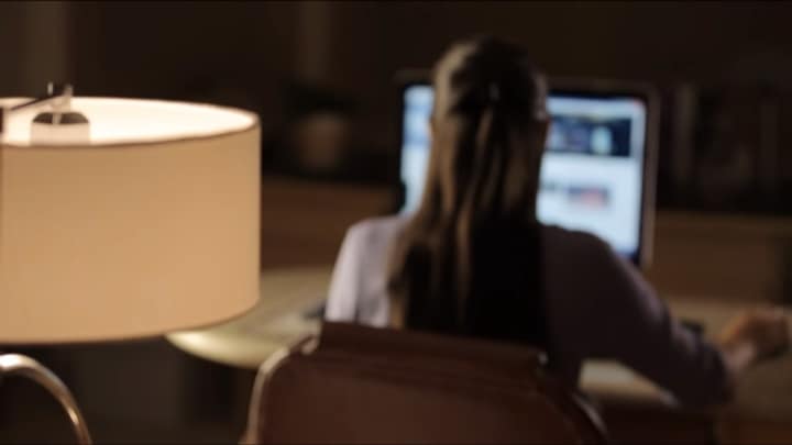 Vrouw die thuis werkt met een bureaulamp op de voorgrond
