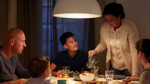 Gezin dat thuis aan het avondeten is aan een goed verlichte eettafel