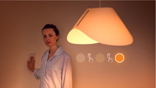 Vrouw die de SceneSwitch lamp instelt op lage helderheid