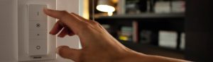 "Handmatig aanpassen van Philips smart LED dimmer, die sfeerverlichting regelt in gezellige woonkamer met boekenplanken."