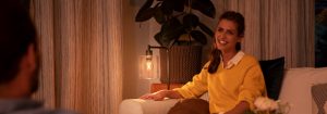 "Gezellige woonkamer sfeer gecreëerd door warme LED tafellamp, verlicht vrouw in gele trui genietend van avondgesprek."