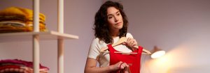 "Warme LED bureaulamp verlicht vrouw die kleding uitzoekt en laat energiezuinige taakverlichting zien voor persoonlijke styling in kastruimte thuis."