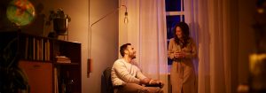 "LED vloerlamp in vintage stijl creëert een warme sfeer voor het avondgesprek van een stel en laat energiezuinige sfeerverlichting zien in een gezellige woonkamer."