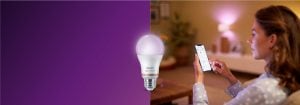 "Vrouw die slimme LED-verlichting bedient via smartphone-app, creëert warme sfeer in gezellige woonkamer met thuis technologie."